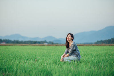 Woman smiling on field against sky