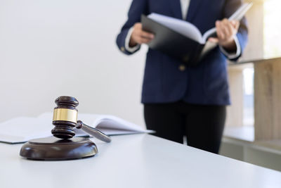 Midsection of judge holding book while standing by table