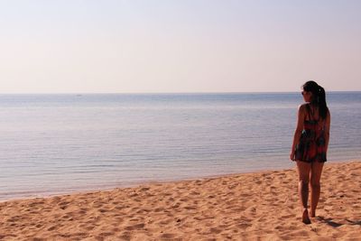 Rear view of woman walking on shore at beach