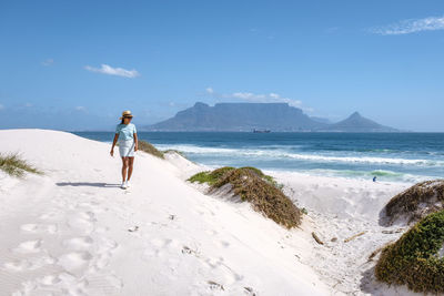 Woman walking on beach against sky