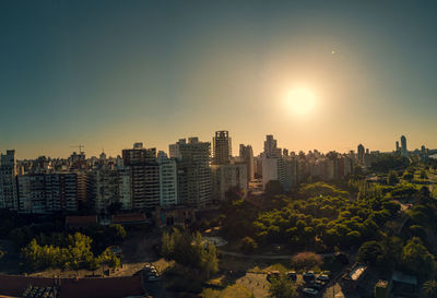 Buildings in city against clear sky during sunset