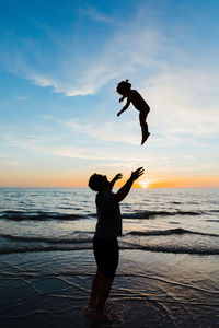 Full length of man jumping on beach against sky during sunset