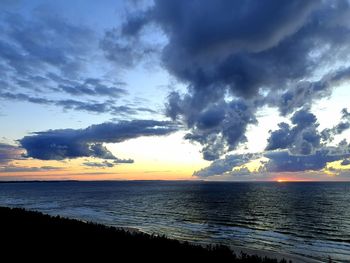 Scenic view of sea against dramatic sky during sunset