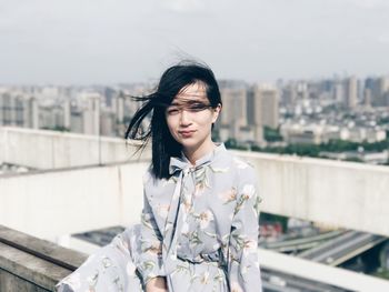 Young woman standing by cityscape against sky