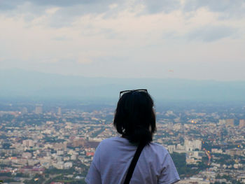 Rear view of woman looking at city against sky