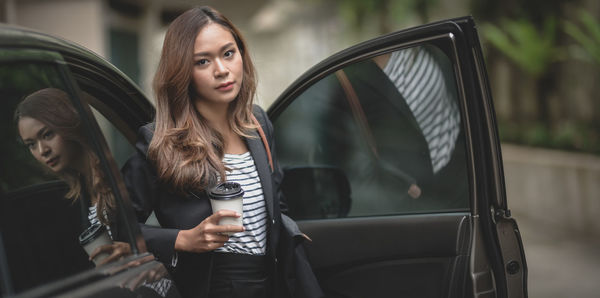 Young woman wearing sunglasses while standing by car