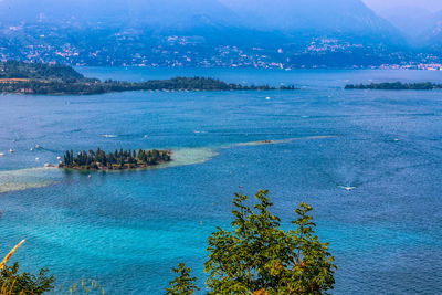 High angle view of sea and trees against blue sky