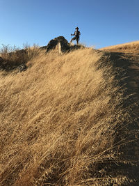 Low angle view of man standing on mountain against clear sky