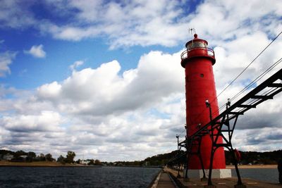 Lighthouse by building against sky