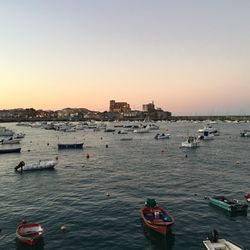 Boats in sea against clear sky during sunset