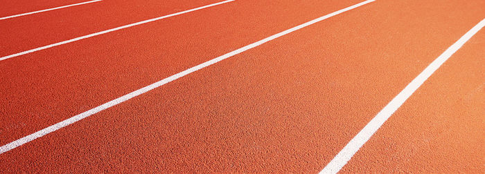 Red running track at stadium with border lanes