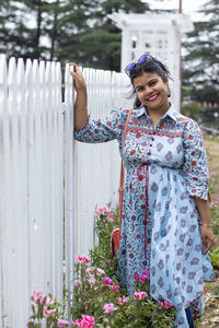 Portrait of young woman standing by plants