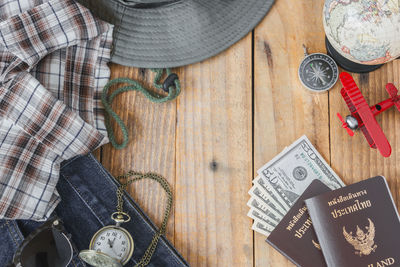 Directly above shot of passport with clothes on wooden table