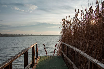 Wooden pier over lake against sky during sunset