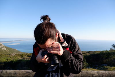 Man photographing against blue sky