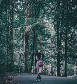 Full length of woman amidst trees in forest