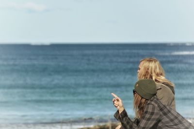 Rear view of woman photographing on beach