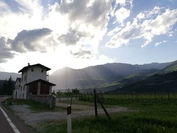 Houses on field by mountains against sky