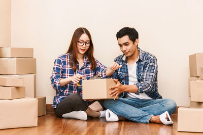 Couple packing box while sitting on floor