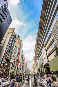 People walking on street against modern buildings in city