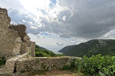 Scenic view of mountains and buildings against cloudy sky