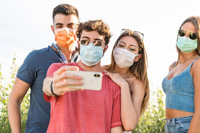 Caucasian millenial friends taking selfie smiling behind face masks