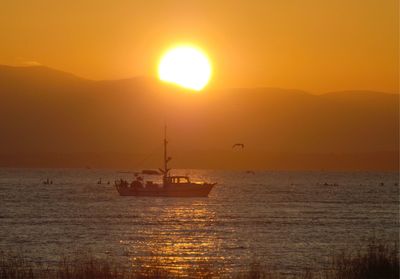 Silhouette sailboat in sea against sky during sunset