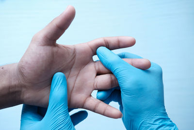 Close-up of hands holding blue over white background