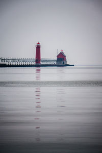 Lighthouse at beach against sky