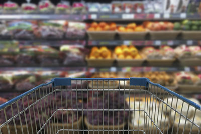 Close-up of shopping cart against shelves