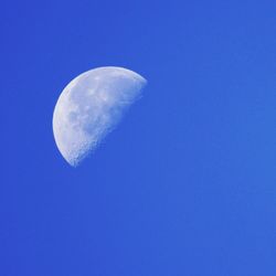 Low angle view of half moon against blue sky