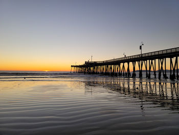 Pier over sea against clear sky during sunset