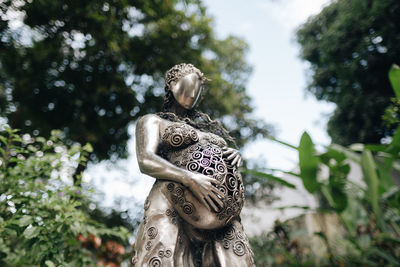 Close-up of angel statue against trees