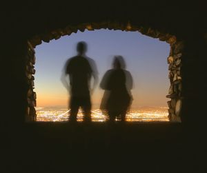 Silhouette people walking against sky during sunset