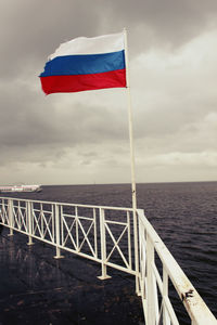 Flag by sea against sky