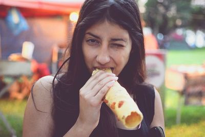 Portrait of young woman eating in city at night