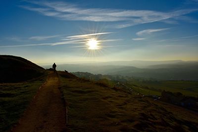 Silhouette of woman on mountain against cloudy sky