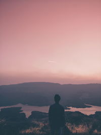 Rear view of silhouette man standing on mountain against sky