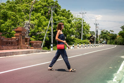 Rear view of woman standing on road against trees