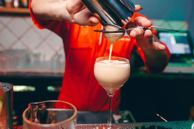 Midsection of bartender preparing drink