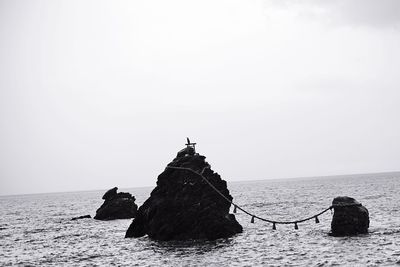 Scenic view of rocks in sea against clear sky