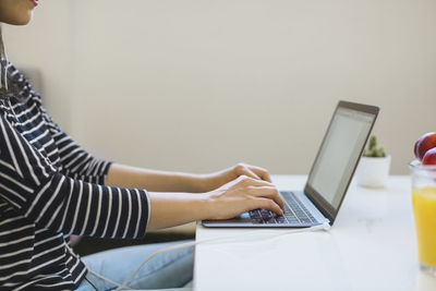 Young woman using laptop at home, partial view