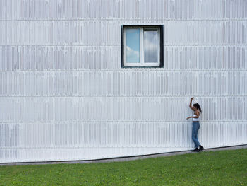 Side view of woman walking against wall