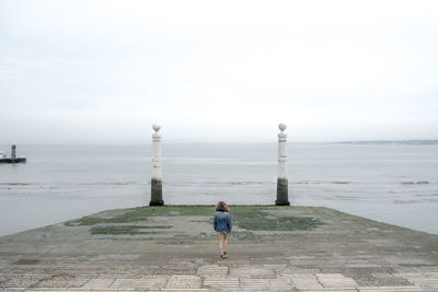 Rear view full length of girl walking on pier against sea