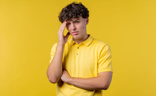 Young woman with arms crossed against yellow background