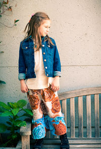 Full length of happy girl standing against wall
