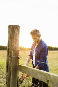 Man holding bolt cutter on grassy field at farm