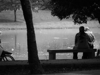 Man sitting on bench by lake