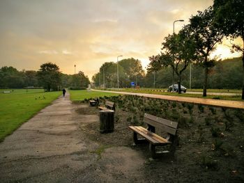 Empty benches in park against sky