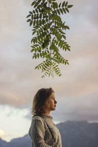 Rear view of woman standing by tree against sky